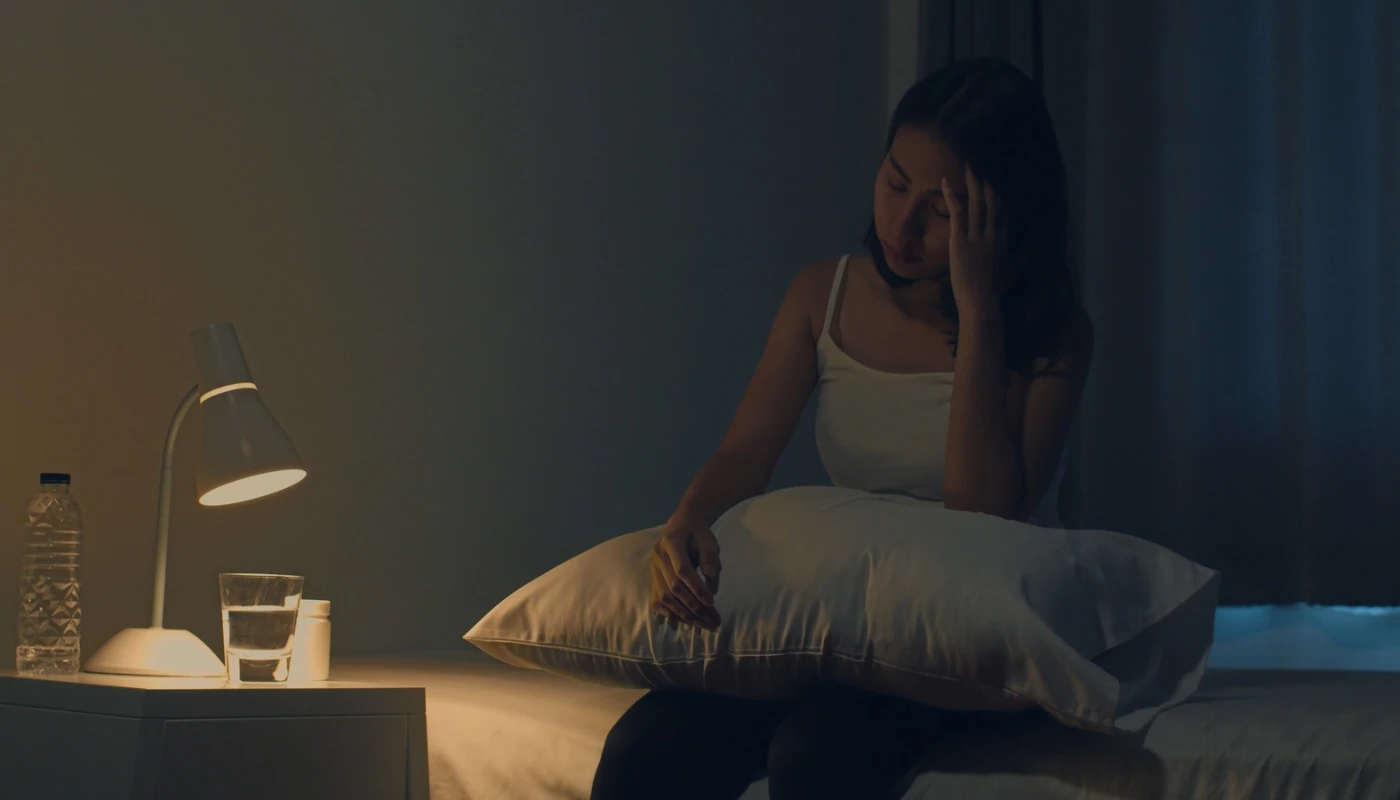 Woman lying awake in bed at night, struggling with overthinking and racing thoughts.